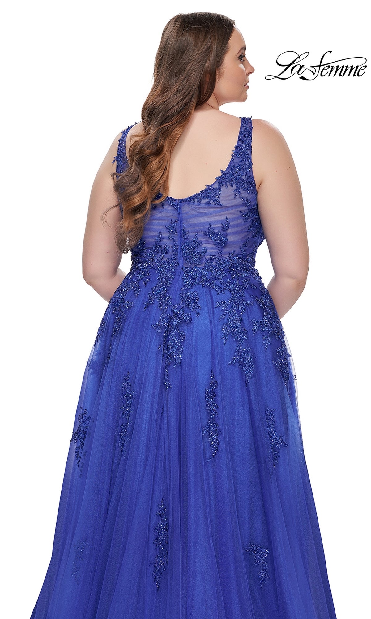 A woman with long brown hair is seen from the back, wearing the La Femme Long Prom Dress 31383—a sleeveless, floor-length royal blue lace dress with embroidered details and delicate beading.